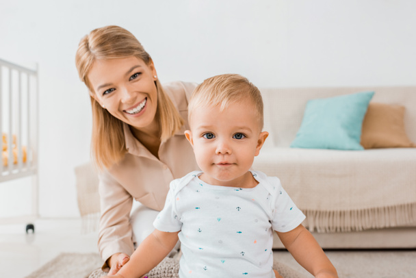 adorable toddler looking at camera with mother in nursery room - Foto, Imagen