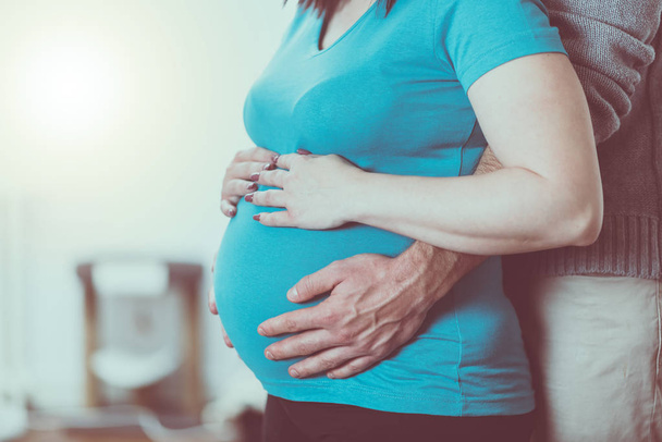 Coppia che si tiene per mano sulla pancia incinta
 - Foto, immagini