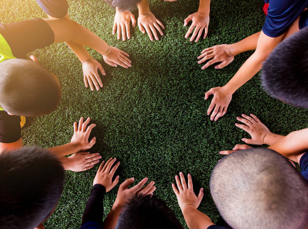 Las manos de los niños en césped artificial verde. Kid fútbol entrenamiento fútbol
. - Foto, Imagen