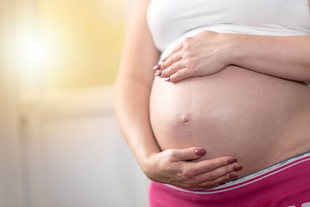 mujer embarazada cogida de la mano sobre su vientre - Foto, Imagen