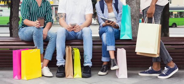 Друзья отдыхают после шоппинга, сидят с разноцветными сумками
 - Фото, изображение