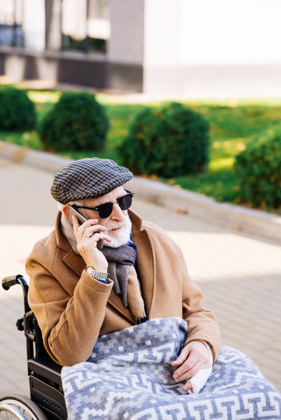 senior disabled man in wheelchair talking by phone on street - Photo, image