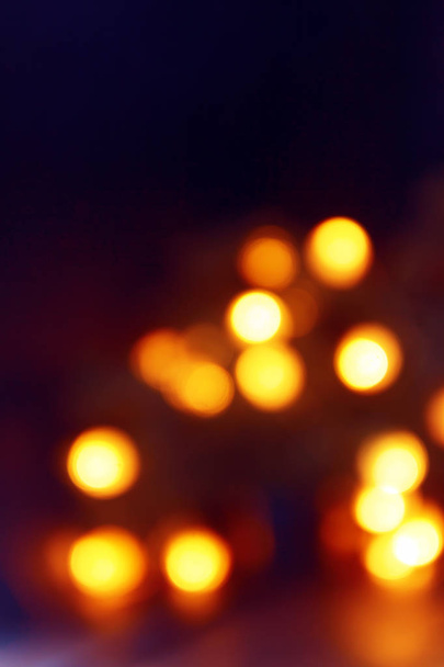 Background of blurry yellow-orange lights of Christmas tree garland on dark. Copy space. - Photo, Image