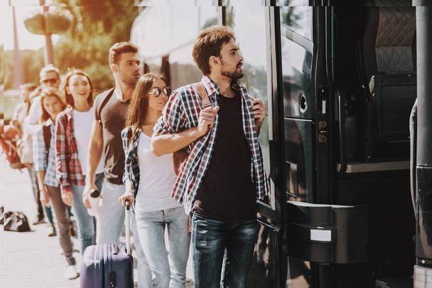Group of Young People Boarding on Travel Bus. Happy Travelers Standing in Queue Holding Luggage Waiting their turn to Enter Bus. Traveling, Tourism and People Concept. Summer Vacation - Fotoğraf, Görsel