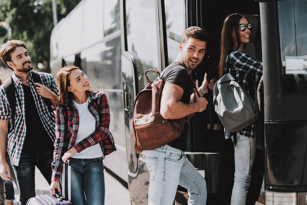 Group of Young People Boarding on Travel Bus. Happy Travelers Standing in Queue Holding Luggage Waiting their turn to Enter Bus. Traveling, Tourism and People Concept. Summer Vacation - Foto, Imagem