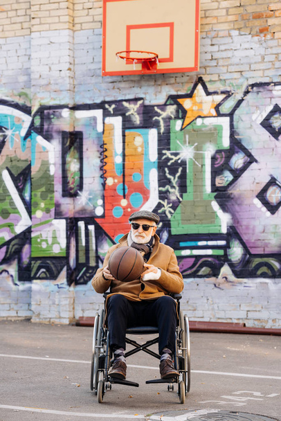 actieve senior uitgeschakeld man in rolstoel met basketbal bal op straat - Foto, afbeelding