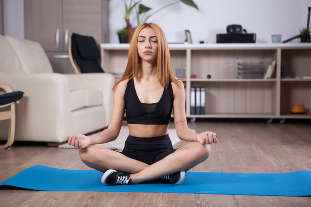 Attraente ragazza seduta in posizione loto yoga nella sua casa
 - Foto, immagini