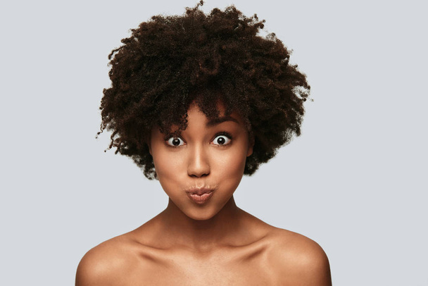 shirtless portrait of young African woman in studio looking at camera and making funny face  - Foto, Bild