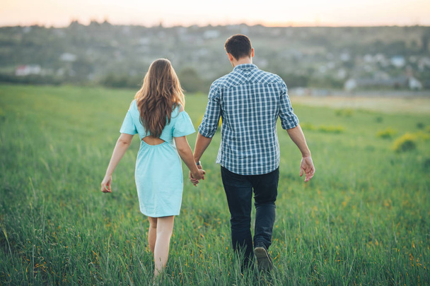 Young couple walking on the field holding hands - Photo, Image