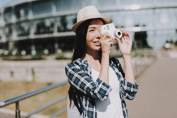 Portrait of Beautiful Woman Taking Photo on Camera. Young Attractive Woman wearing Hat and Checkered Shirt closing Face with White Camera. Smiling Happy Girl Enjoying Sunny Day. Creative Photographer - Zdjęcie, obraz