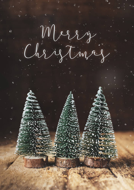 Merry Christmas with xmas tree and snow falling on grunge wood table and dark brown wooden wall.winter holiday greeting card - Foto, immagini