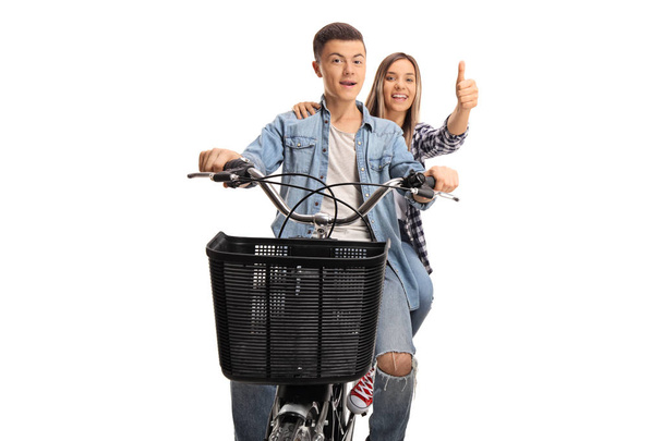 Smiling boy and girl riding on the same bike and giving thumbs up isolated on white background - Foto, Imagem