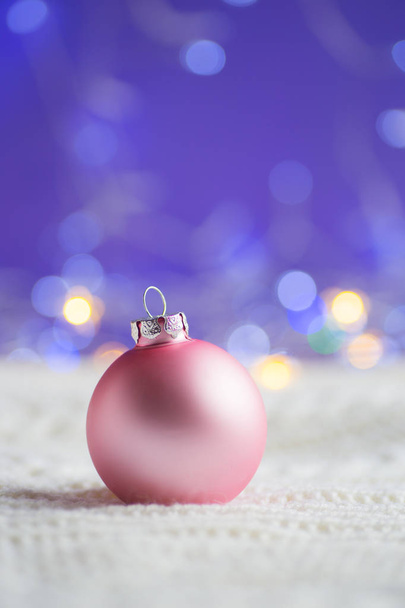 白地にパステル ピンクのクリスマス ボール ニット生地暖かいボケ味を持つ紫色の背景に。年賀状。クリスマス装飾. - 写真・画像