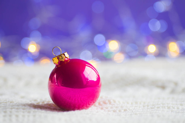 温かみのあるボケ味を持つ紫色の背景に白のニット生地でクリムゾンのクリスマス ボール。年賀状。クリスマス装飾. - 写真・画像