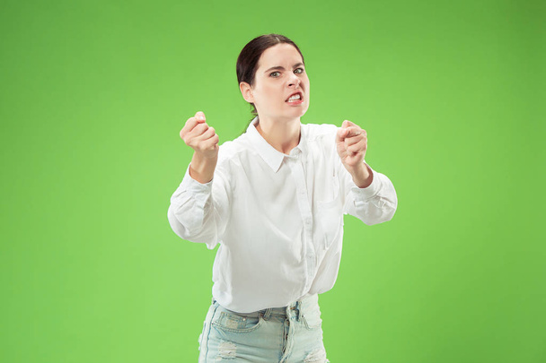 Portrait of an angry woman looking at camera isolated on a green background - Φωτογραφία, εικόνα