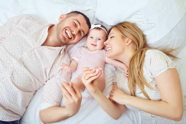 Mother and father play with the baby on the bed. - Foto, Bild