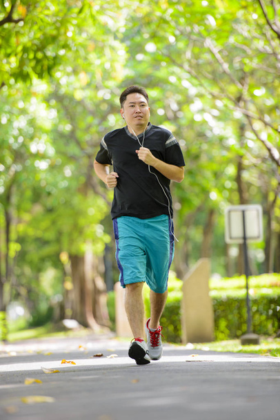 asiático hombre usando auriculares corriendo en parque
 - Foto, imagen