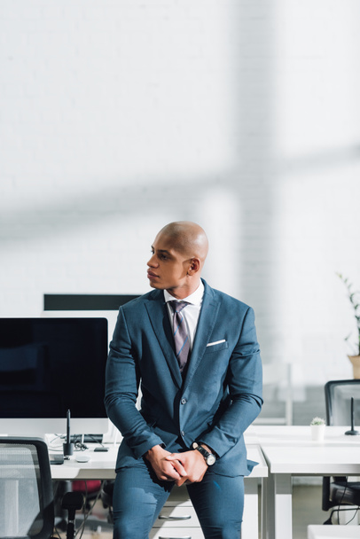 молодий афроамериканець бізнесмен дивитися вбік, сидячи в офісі - Фото, зображення