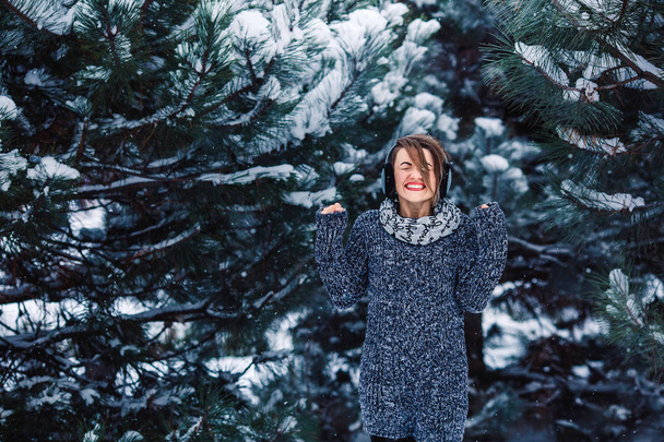 Stylish cheerful girl in a sweater in the winter forest. - Photo, Image