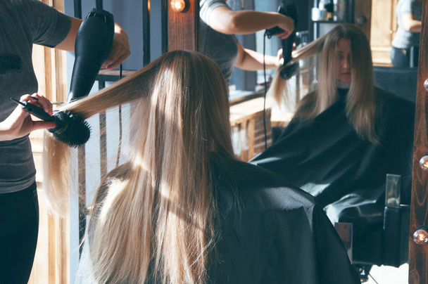 Uma linda garota loira europeia fazendo um penteado em um salão de beleza
 - Foto, Imagem