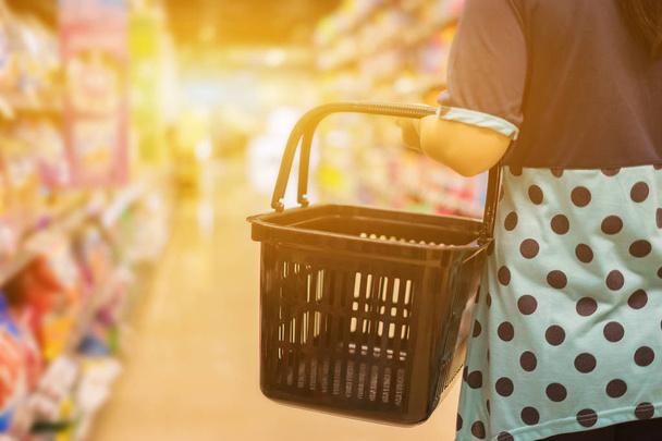 abgeschnittenes Bild einer Frau beim Einkaufen mit Einkaufskorb im Geschäft - Foto, Bild