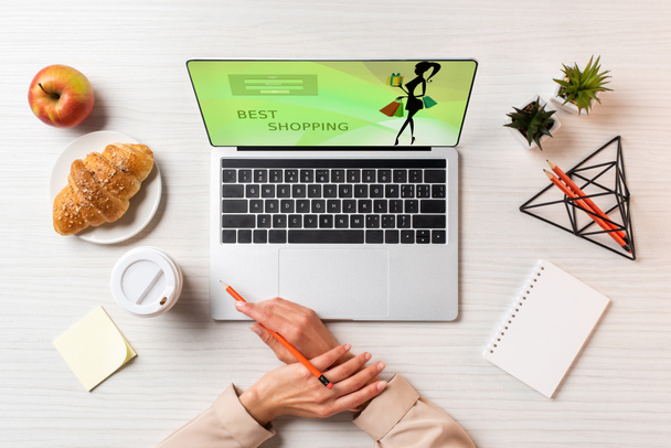 περικοπεί shot γυναικεία χέρια, φορητό υπολογιστή με καλύτερη εμπορική ιστοσελίδα και γεύμα στο τραπέζι στο γραφείο        - Φωτογραφία, εικόνα