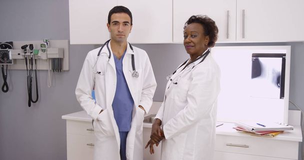 Two medical doctors standing inside office looking at camera - Photo, Image