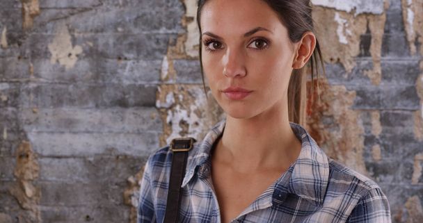 Muotokuva kaunis nuori nainen sininen ruudullinen paita poseeraa vakavasti vanha seinä
 - Valokuva, kuva