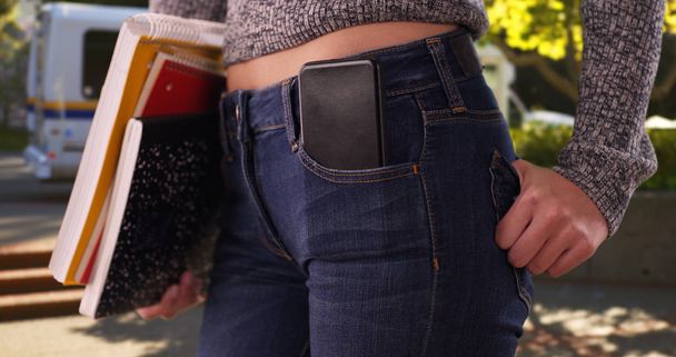 Chica universitaria con libros y teléfono en el bolsillo en el campus después de bajar del autobús
 - Foto, Imagen