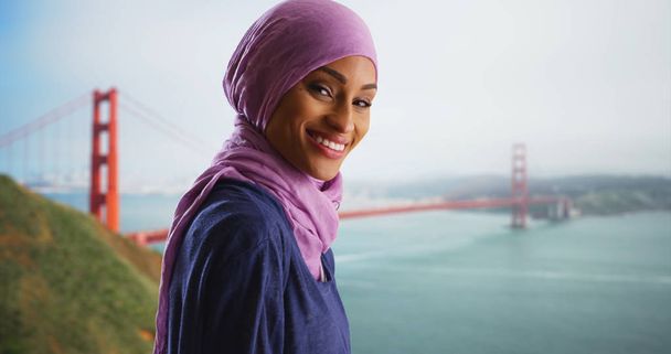 Houkutteleva musta nainen hijabissa vierailulla Golden Gate Bridge hymyilee kameralle
 - Valokuva, kuva