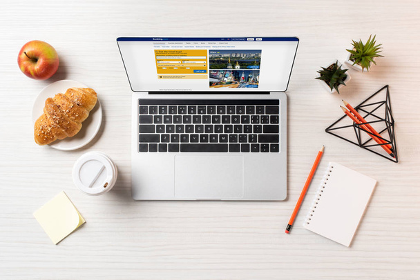 Widok z góry laptopa z rezerwacji internetowej, rogalik i kawa na wynos na office tabela    - Zdjęcie, obraz