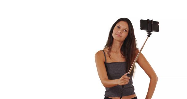 mignonne brunette voyageur fille en utilisant selfie stick en studio avec espace de copie
 - Photo, image
