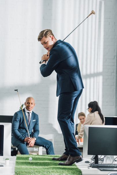 jovens empresários multiétnicos em vestuário formal jogar golfe no escritório
 - Foto, Imagem