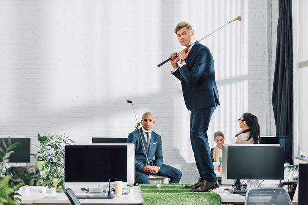 young multiracial businessmen playing golf in open space office - Photo, Image