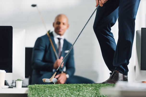 low section of young businessman playing golf in office - Photo, Image