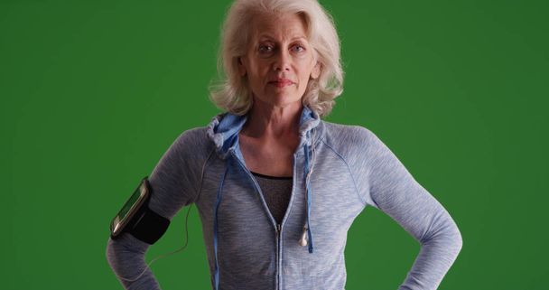 Серьёзно выглядящая старая белая женщина позирует в спортивной одежде на зелёном экране
 - Фото, изображение