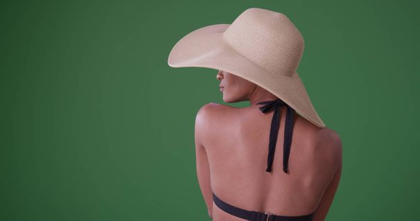 Pohled zezadu afroamerické ženy v bikinách a klobouk na zelené obrazovce - Fotografie, Obrázek