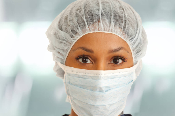 Close up of female surgeon wearing mask and hair net inside hospital - Foto, immagini