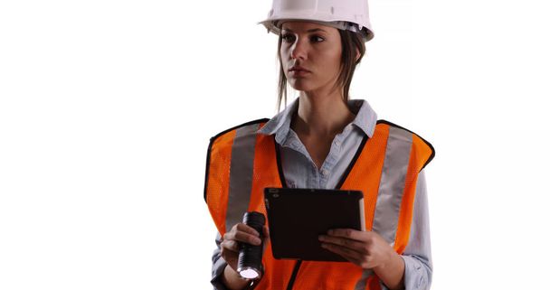Mulher trabalhadora em equipamento de segurança com tablet e lanterna no espaço de cópia em branco sólido
 - Foto, Imagem