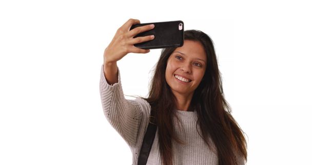 Hermosa hembra en suéter gris toma selfie teléfono sobre fondo blanco
 - Foto, imagen