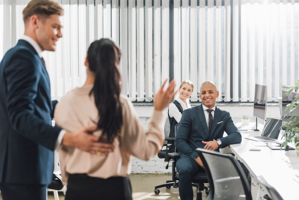 smiling businessman looking at new colleague waving hand and greeting coworkers in office  - Foto, Imagem