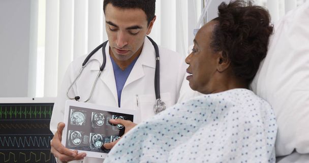 Portrait of hispanic medical doctor showing ct-scans on tablet to patient - Photo, Image
