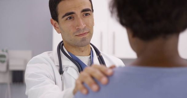 Adorável masculino latino médico colocando a mão sobre os pacientes ombro e confortá-la
 - Foto, Imagem