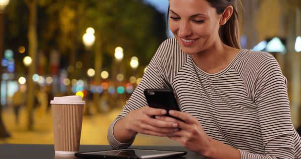 junge Dame sitzt am Cafétisch und textet mit dem Handy auf den Champs-Élysées in Paris - Foto, Bild