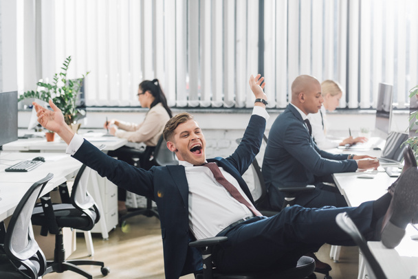 excited young businessman triumphing while working in office - Фото, изображение