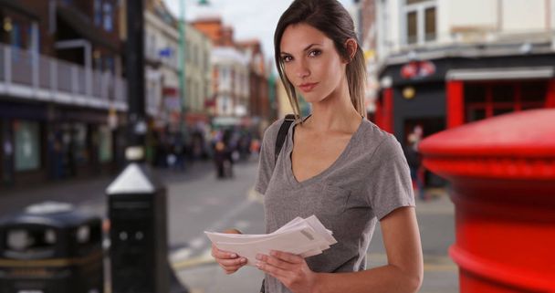 Millennial girl with letters in hand looking at camera in European city setting - Photo, Image