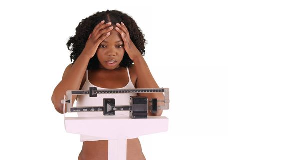 unglückliche junge schwarze Frau wiegt sich im Studio mit Kopierraum auf einer Waage - Foto, Bild