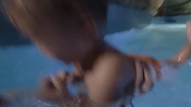 Szczęśliwa młoda matka trzyma synka na ręce, uśmiechając się i bawić się z nim w basenie. - Materiał filmowy, wideo