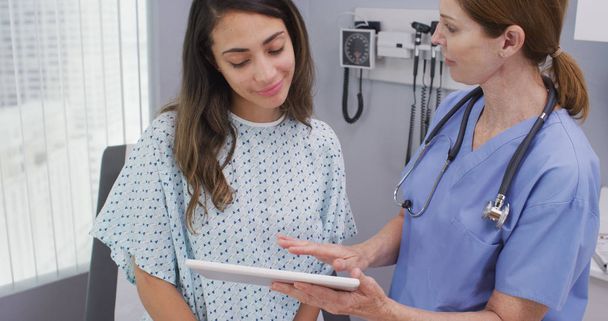 Nahaufnahme einer Krankenschwester mit Tablet-Computer, um Testergebnisse mit dem Patienten zu teilen - Foto, Bild