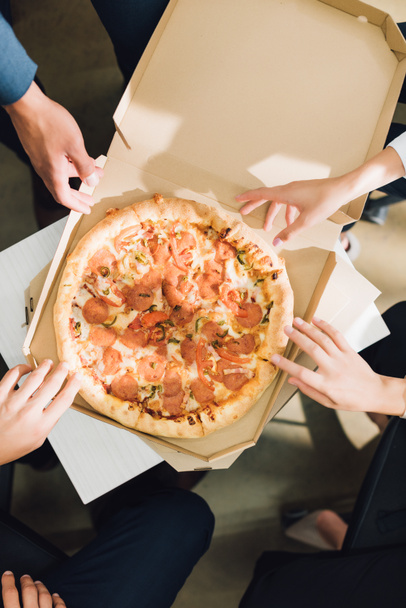 cropped shot of young coworkers eating pizza in office  - Fotografie, Obrázek